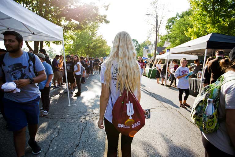 a woman with an Indiana University backpack at an outdoor street fair