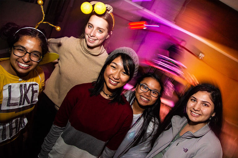 five smiling female students, two are wearing headbands with silly antennae