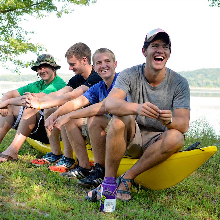 four young men sitting on a kayak