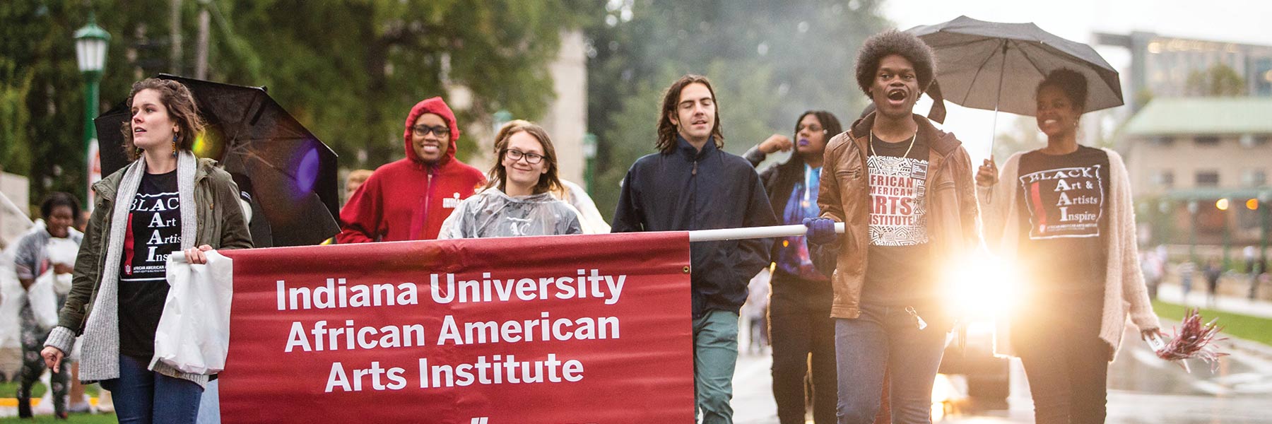 students in a parade holding a banner for the Indiana University African American arts institute