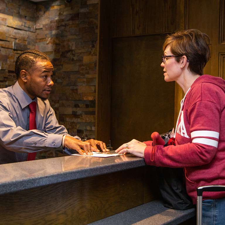 an employee of the Biddle hotel speaks to a guest at a reception counter