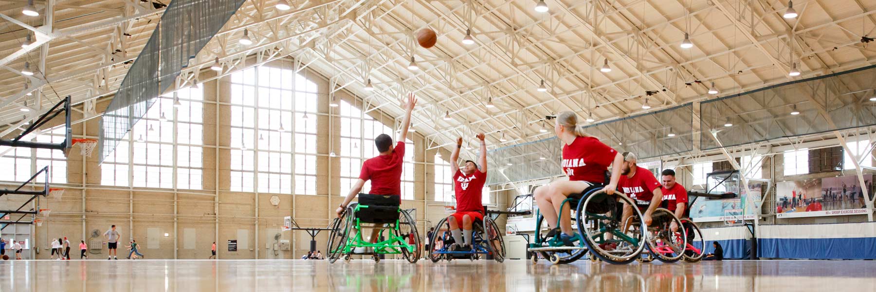 five people in wheelchairs playing basketball