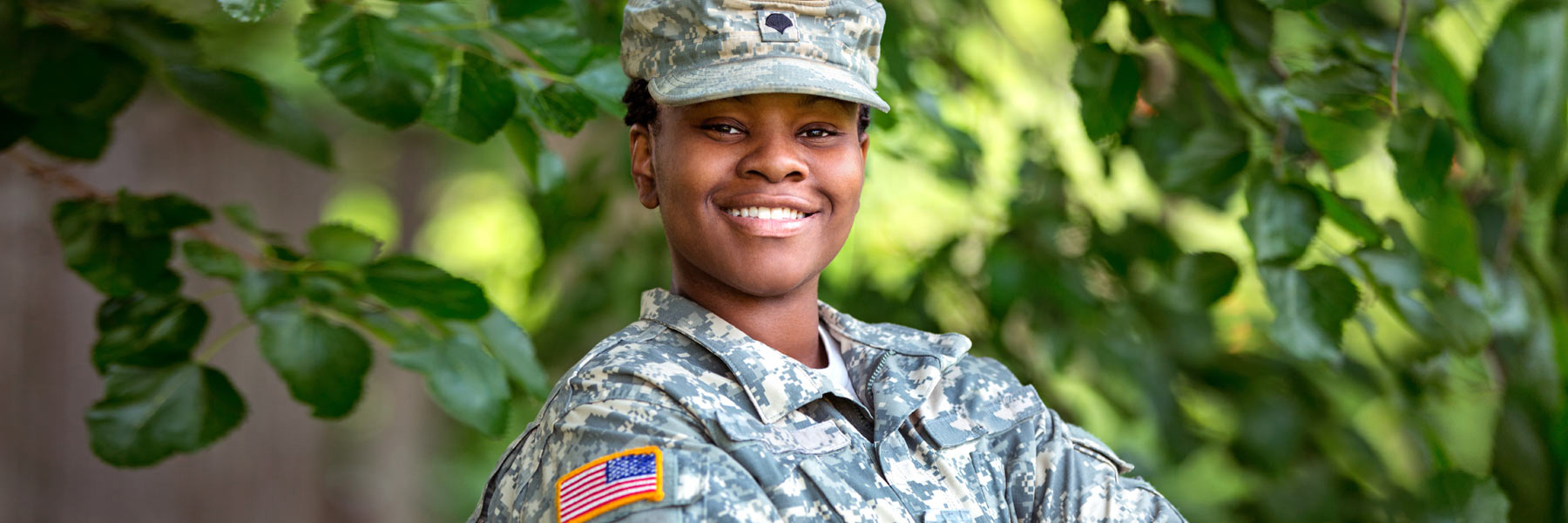 a woman smiling in a camouflage US army uniform